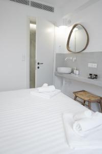 een witte slaapkamer met een groot bed en een spiegel bij Olvio Suites in Kardhamili