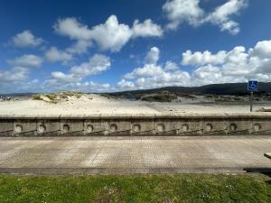a stone wall next to a road and a beach at A Terraza By Oktheway in Laxe
