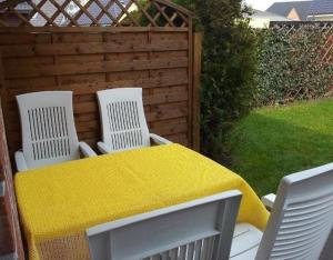 een tafel en vier stoelen met een gele tafelkleed bij Appartement in Burg Auf Fehmarn mit Terrasse, Garten und Grill in Fehmarn