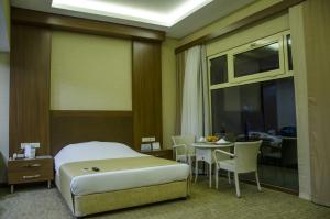 1 dormitorio con 1 cama y 1 mesa con sillas en Hotel Tilmen, en Gaziantep