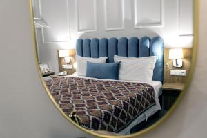 Schlafzimmer mit einem Bett mit blauem Kopfteil und einem Spiegel in der Unterkunft Paradise Hotel in Parga