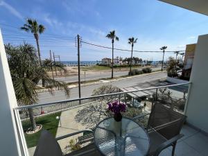 balcón con mesa de cristal y vistas a la playa en Themis Apartments en Lárnaca