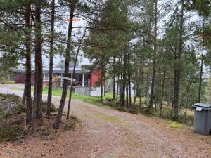 Eine unbefestigte Straße, die zu einem roten Haus im Wald führt. in der Unterkunft Värmdö in Värmdö