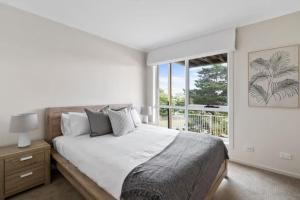 a white bedroom with a large bed and a window at Water View Home - Minutes To Town in Batemans Bay