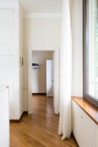 um corredor com paredes brancas e pisos de madeira e uma janela em Villa Noseda em Moltrasio