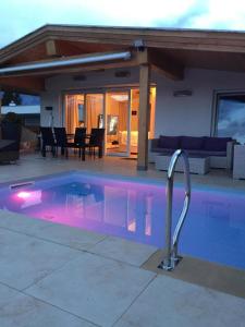 - une piscine avec éclairage violet en face d'une maison dans l'établissement Ferienhaus in Seefeld In Tirol mit Großer Terrasse, à Seefeld in Tirol