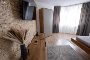 sala de estar con TV en una pared de ladrillo en La Bubu Apartament, en Zărneşti