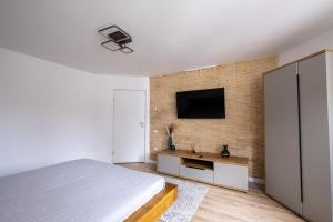 Un dormitorio con una cama y un televisor en una pared. en La Bubu Apartament, en Zărneşti
