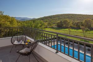 einen Balkon mit 2 Stühlen, einem Tisch und einem Pool in der Unterkunft Ferienhaus für 6 Personen ca 150 qm in Sičane, Dalmatien Dalmatinisches Hinterland in Sičane