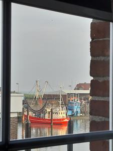 un bateau rouge est amarré dans l'eau par une fenêtre dans l'établissement Apartment Krabbe, à Fedderwardersiel