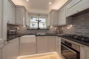 a kitchen with white cabinets and a sink at Chy An Gweal Farm Cottage in Carbis Bay