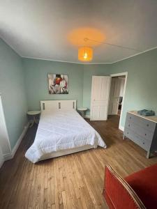 Schlafzimmer mit einem weißen Bett und Holzboden in der Unterkunft La cigalienne in Treignac