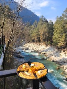 un piatto di cibo seduto su un tavolo accanto a un fiume di Forest View by The Delhi Heights Kasol a Kasol