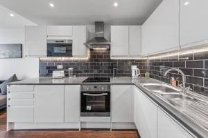 a white kitchen with a stove and a sink at New Apartment 20 mins from Waterloo London BP36 in London