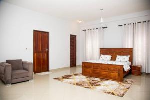 a bedroom with a bed and a chair at Masaki Seaside Charm: Spacious Hideaway in Dar es Salaam