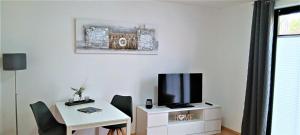 een woonkamer met een tv en een tafel met stoelen bij Waldblick Nordhorn in Nordhorn