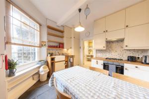 a kitchen with white cabinets and a table in it at Beautiful 1 Bedroom Flat in Vibrant Stockbridge in Edinburgh