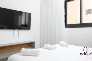 2 weiße Betten in einem Zimmer mit einem Flachbild-TV in der Unterkunft דירת משפחתית 2 חדרי שינה במיקום מרכזי - By Edom in Eilat