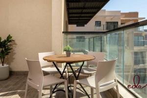 einen Holztisch und weiße Stühle auf dem Balkon in der Unterkunft דירת משפחתית 2 חדרי שינה במיקום מרכזי - By Edom in Eilat