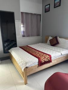 1 dormitorio con 1 cama grande con marco de madera en KHÁCH SẠN NGUYỄN LONG en Thap Muoi