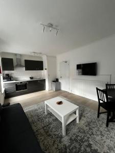 a living room with a white table and a kitchen at Cosy one-bedroom furnished flat! in Seven Kings