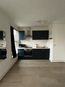 a kitchen with black and white appliances in a room at Cosy one-bedroom furnished flat! in Seven Kings