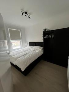 Seven KingsにあるCosy one-bedroom furnished flat!の白い部屋に大型ベッド1台が備わるベッドルーム1室が備わります。
