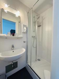 a white bathroom with a sink and a shower at Hotel Wendelstein in Rosenheim +67 photos