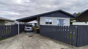 a car parked in front of a house with a fence at Charisma Homestay in Invercargill