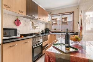 een keuken met houten kasten en een aanrecht met een fles wijn bij Costamar Arinaga in Arinaga