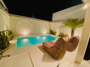 una piscina con divano e sedia accanto di Villa Two Bedroom Mediterranean White House a Pesanggaran