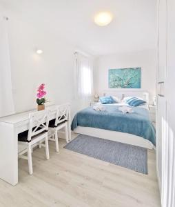een witte slaapkamer met een bed en een bureau bij Komfortable Wohnung in ruhigem Dorf in Umag