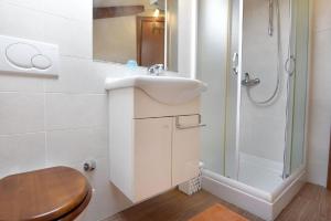 een witte badkamer met een wastafel en een douche bij Komfortable Wohnung in ruhigem Dorf in Umag