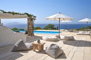 a patio with pillows and an umbrella and a pool at VILLA EKAVI FILIZI - Seaside Residence just outside of Naousa in Naousa