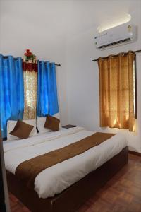 a bedroom with a large bed with blue curtains at Noble Homestay in Munnar