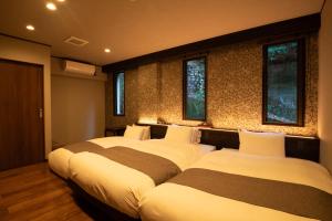 2 camas en una habitación con ventanas en Kikunoya en Miyajima