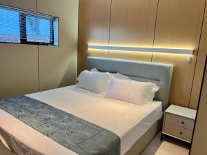 um quarto com uma cama com lençóis brancos e almofadas em Guesthouse in a villa North Shore minutes from CBD em Auckland