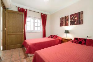 2 camas en una habitación con sábanas rojas en Casa Paca, en Maspalomas