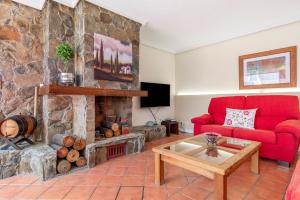 sala de estar con sofá rojo y chimenea de piedra en Casa Paca, en Maspalomas
