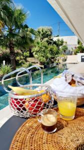 - une corbeille de fruits et des boissons sur une table à côté de la piscine dans l'établissement COTTAGE MARIN avec VUE MER, à Nice
