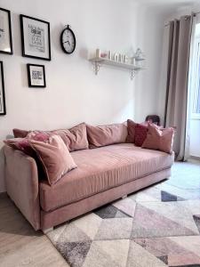 un divano in un soggiorno con un orologio sul muro di PEBBLE Apartman ZADAR a Zara (Zadar)