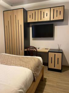 a bedroom with a bed and a desk with a television at Saphir Boutique Hotel in Kigali