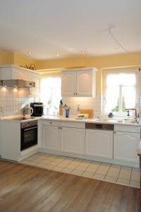 a kitchen with white cabinets and white appliances at Gud Tidj - Whg 03 in Wyk auf Föhr