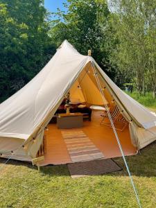 a canvas tent with a wooden deck in a field at Cherry Bell Tent in Droitwich
