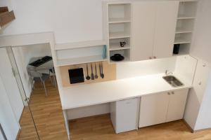 een keuken met witte kasten en een wastafel bij Gemütliches Studio mit Hochbett im Herzen von Graz in Graz
