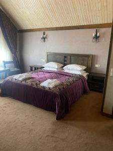 a bedroom with a large bed with purple sheets and pillows at Shale Anemona in Bukovel