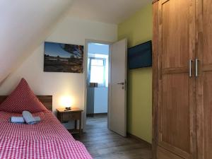 um quarto com uma cama com um cobertor vermelho e uma porta em Haus Felsenbirne im Bispinger Heidezauber em Bispingen