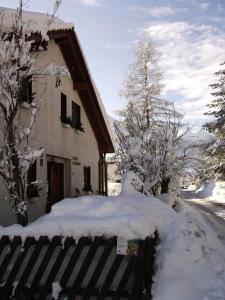 a house covered in snow next to a fence at Ferienwohnung mit Weinlaube in Imst mit Terrasse, Grill und Garten in Imst