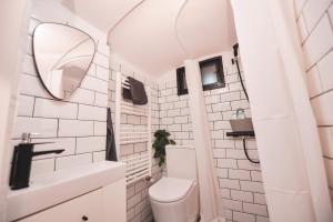 a white bathroom with a toilet and a mirror at Music Xperience Studio- comfy basement for Music Lovers in Timişoara