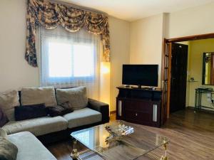 ein Wohnzimmer mit Couch und Flachbildfernseher in der Unterkunft Liebevoll eingerichtetes Ferienhaus mit Meerblick von der schönen Dachterrasse und eigenem Obstgarten in Las Galletas